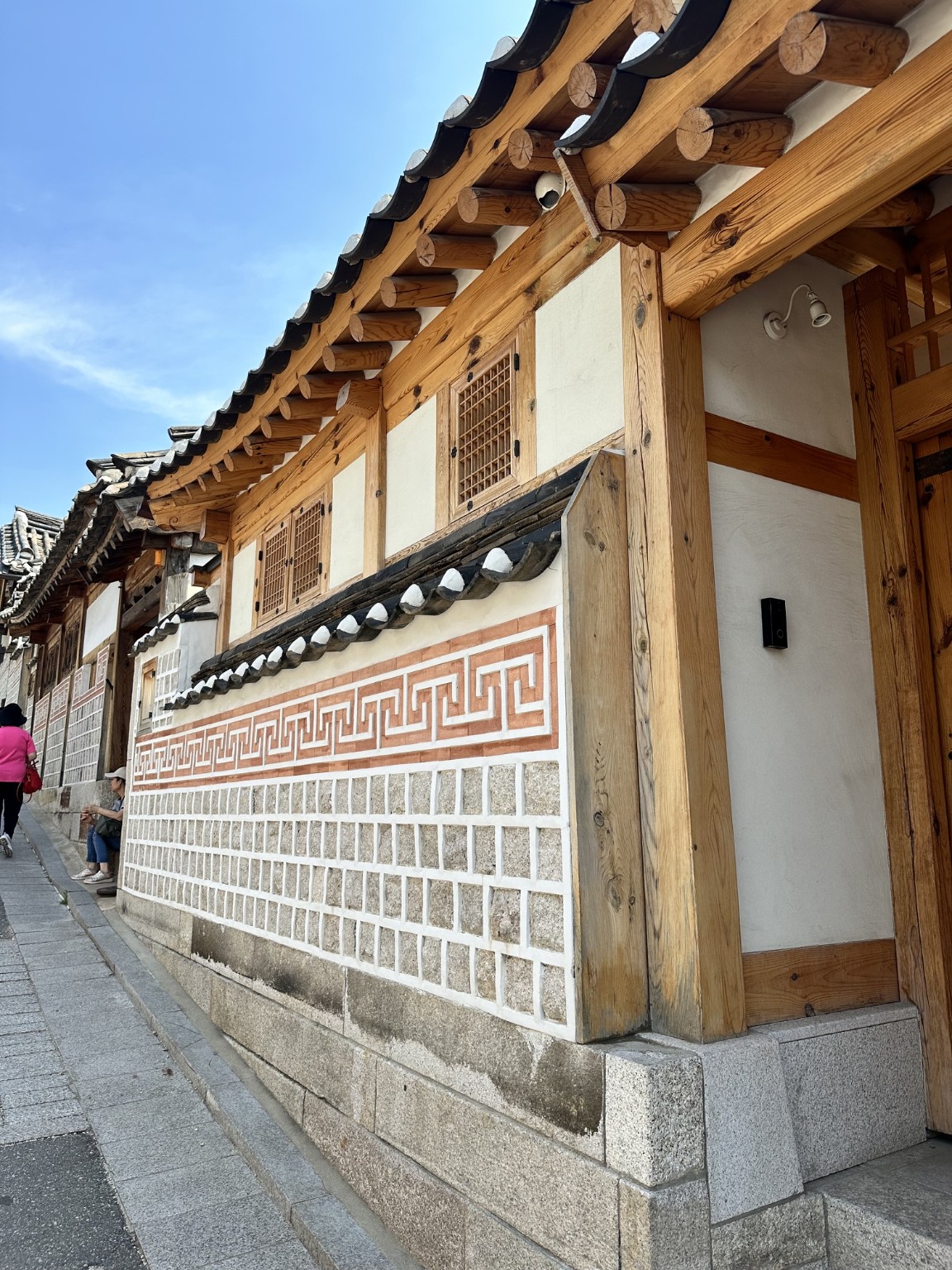 Timber beams, tiled eaves and a patterned wall on a traditional building in Seoul
